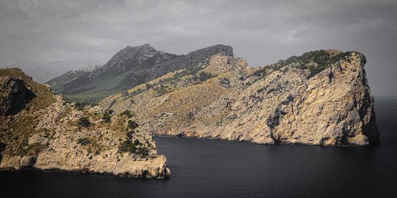 一片宁静的公园,一位男士坐在长椅上,手中捧着一块刻有字的石头,远处飘着落叶,营造一种沉思的氛围