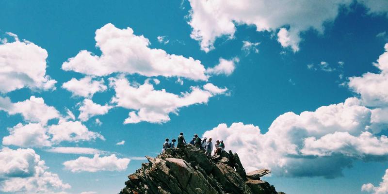 一群年轻人穿着运动装备，在城市的废墟或者高楼之间进行攀岩、跑酷等极限运动，背景中隐约可见城市的繁华景象。